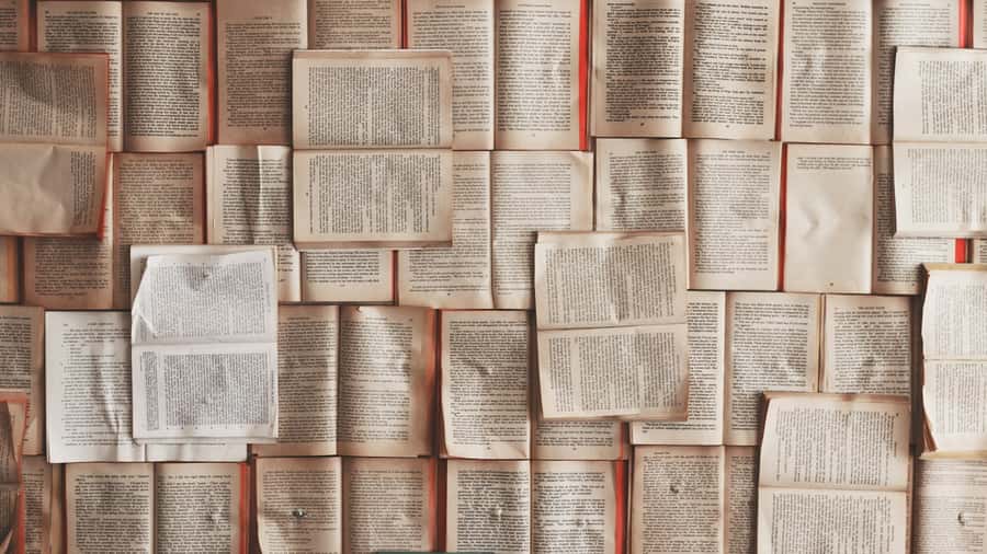 Dozens of open books laid out flat in a grid, pages of dense printed text